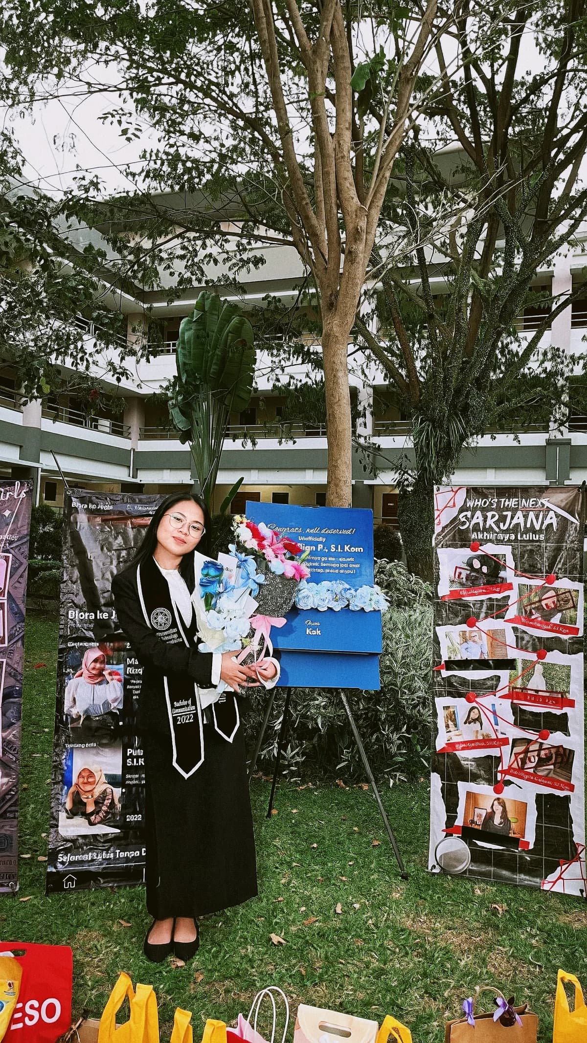 Ayu mengenakan toga dan memegang buket saat wisuda.